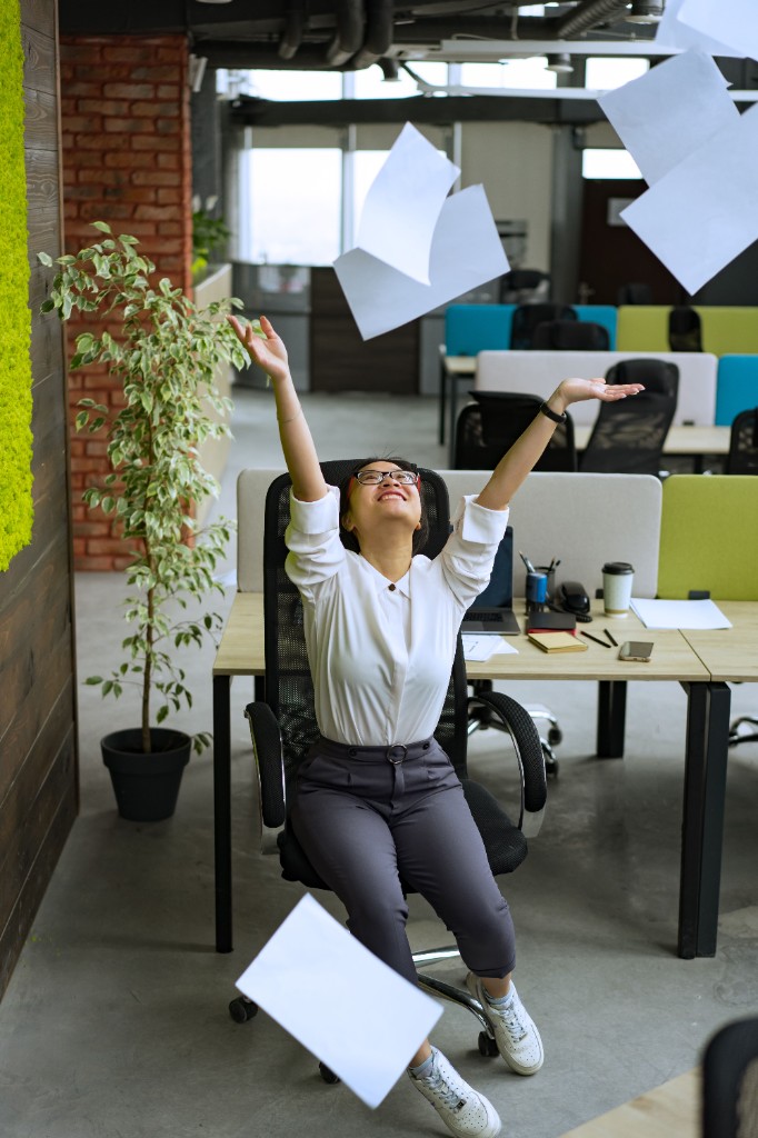 Happy entrepreneur tossing papers in the air in the office